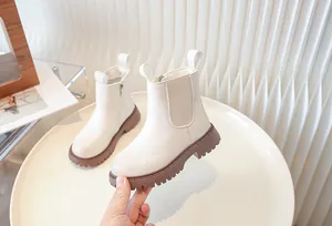 Detailed view of white children's Chelsea boots with brown lug soles and side zipper