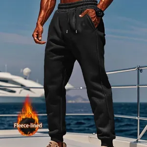 A detailed close-up of men's black fleece-lined joggers worn on a luxury yacht deck setting