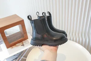 Detailed side view of children's black British style leather Martin boots held by hand