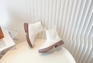Professional detail view of cream white kids Chelsea boots featuring chunky brown lug soles