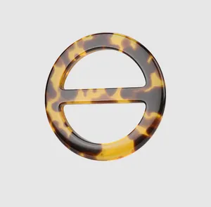 Detailed view of a circular tortoiseshell resin button with a horizontal center bar.