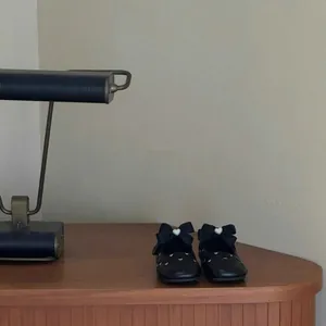 Vintage style black girls' Mary Jane shoes with large bow accents on a wooden desk