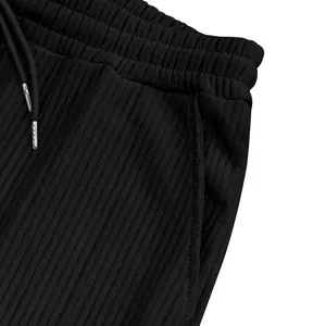 Primer plano del tejido acanalado negro y la cintura con cordón de un pantalón de hombre.