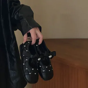 Detailed view of black quilted girls' Mary Jane shoes with heart print and bow