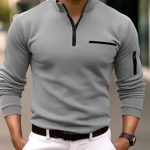 Dettaglio di polo da uomo grigia a coste con mezza zip e taschino con cerniera