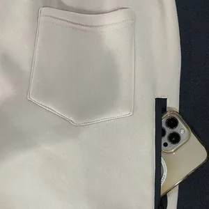 Close-up of beige fleece sweatpants showing functional zipper side pocket and back pocket