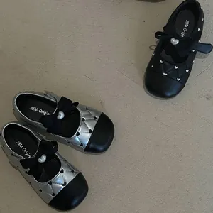 Detailed view of girls' bow leather shoes with heart embroidery and pearl accents.