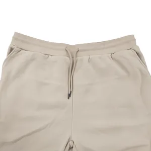 Close-up view of the comfortable elastic waistband and drawstring on beige men's joggers.