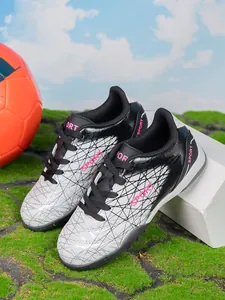 Detailed close-up view of silver and black children's soccer cleats on green turf grass