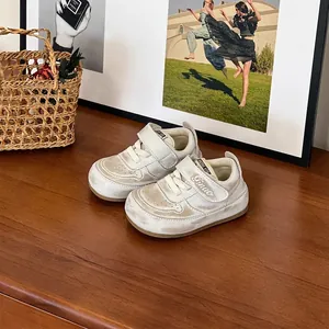Gros plan de baskets crème pour tout-petits avec bandes velcro sur du bois.