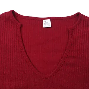 Detail view of burgundy V-neck men's knit shirt with ribbed texture and care label.