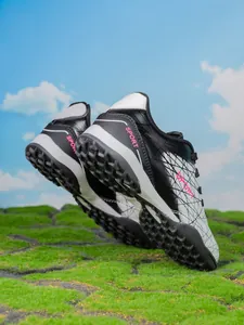 Detailed macro view of durable kids' turf soccer shoes with rubber cleats on grass