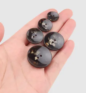 Detailed macro view of high-end tortoise shell resin buttons held in hand for scale