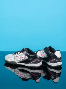 Detailed view of kids' TF soccer shoes with geometric patterns and pink accents