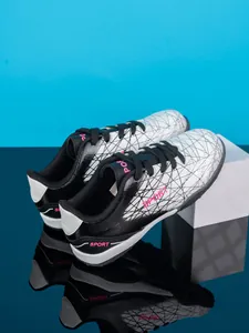 Close-up of black and white kids turf soccer shoes with pink Sport text and geometric pattern