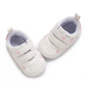 Detail of white baby sneakers with pink heart embroidery and velcro straps