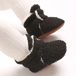 Detailansicht schwarzer Plüsch-Babyschuhe mit weichen Sohlen und weißem Kunstfellbesatz.
