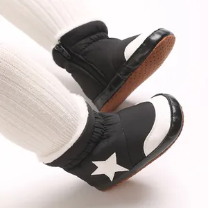 Gros plan de bottes d'hiver pour bébé noires et blanches avec motif d'étoile et semelle