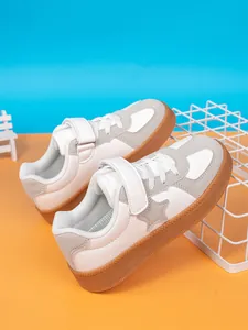 Detail of boys' white sneakers with star patch and durable gum sole in a vibrant studio setting.