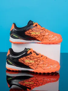 Detailed side view of orange and black boys TF soccer shoes with clear reflection