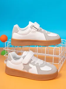 Detailed view of children's white and grey sneakers with durable gum soles and star pattern