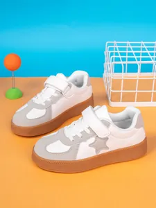 Stylish children's white sneakers with star detail and gum soles, 45-degree view.