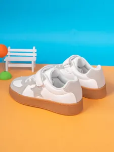 Close-up of white and grey children's sneakers with Velcro straps and durable gum soles.