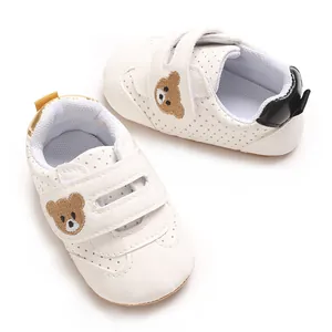 Vista detallada de zapatos de bebé blancos con lindo bordado de oso pardo pequeño