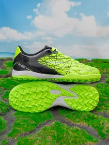 Close-up of boys neon green soccer shoes with textured turf soles for training
