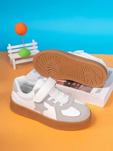 Close-up of white and grey children's sneakers with star design and textured brown sole.