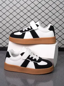 Vista detallada de las zapatillas blancas y negras para niños con suela de goma resistente.