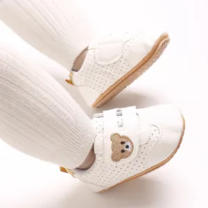Primer plano de zapatos blancos para bebé con bordado de oso y cierre de tira de velcro