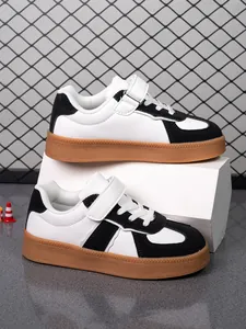 Vista lateral de zapatos casuales para niños en blanco y negro con suelas de goma