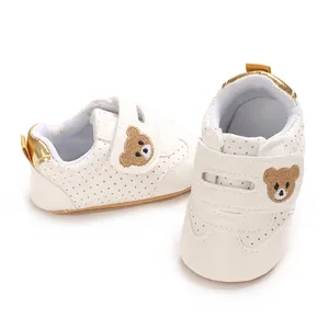 Primer plano de zapatos para bebé con bordado de osito y detalles perforados