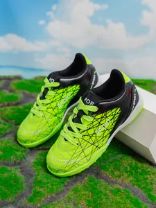 Detail view of vibrant neon green and black children's turf soccer shoes with durable studs