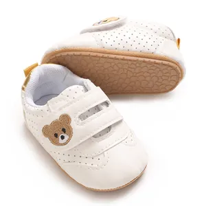 Detalle de zapatos de bebé blancos con bordado de oso y suela antideslizante para caminar