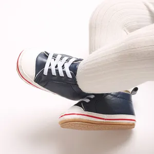 Detailopname van marineblauwe babyschoentjes met witte zachte zolen en geribbelde legging.