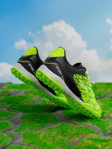 Detail of green and black boys' soccer shoes showing turf cleats and heel design.