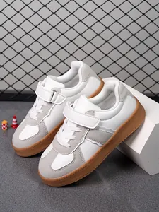 Detalle de zapatillas blancas para niños con suela de goma color caramelo y velcro