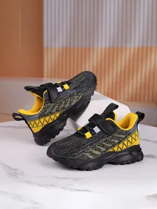 Detailed view of breathable black and yellow mesh sneakers for boys and girls on marble