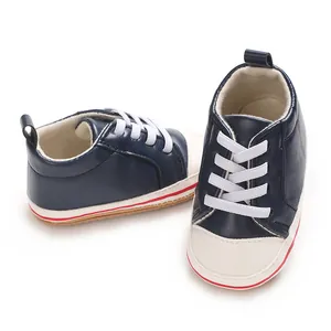Gedetailleerd zicht op marineblauwe baby-sneakers met witte zachte zolen en vetersluiting.