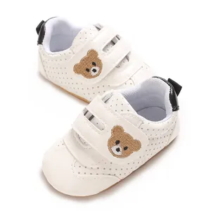 Vista detallada de zapatos blancos para bebés con un lindo motivo de oso pardo bordado