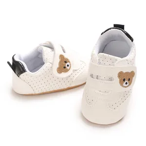 Detalle de zapatos de bebé blancos para caminar con bordado de oso y cierre de velcro