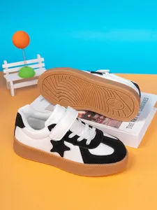 Macro detail of black and white kids' star sneakers featuring durable gum rubber soles.