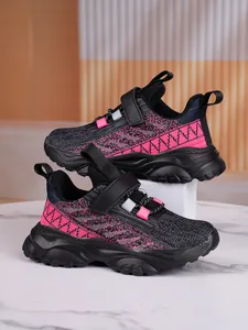 Detail view of breathable pink and black knit texture on kids sports sneakers.