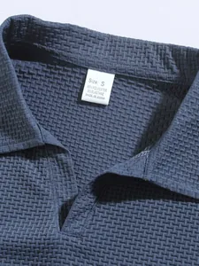 Detailed macro view of blue men's polo shirt featuring textured waffle fabric and label.