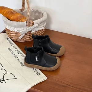 Detailed view of black toddler leather boots with side zipper and durable brown rubber sole