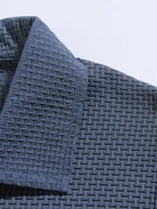 Detail close-up of a blue men's polo shirt featuring a textured waffle weave fabric.