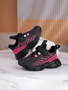 Close-up of pink and black kids' breathable athletic sneakers with durable thick soles.