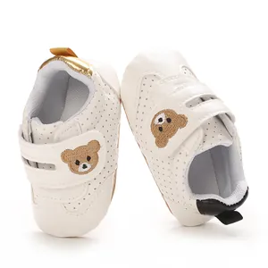 Detail view of white baby walking shoes with cute bear embroidery and breathable holes